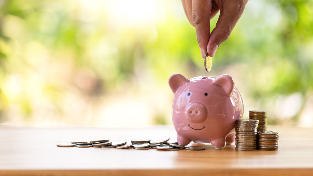 Person putting coins in a piggy bank