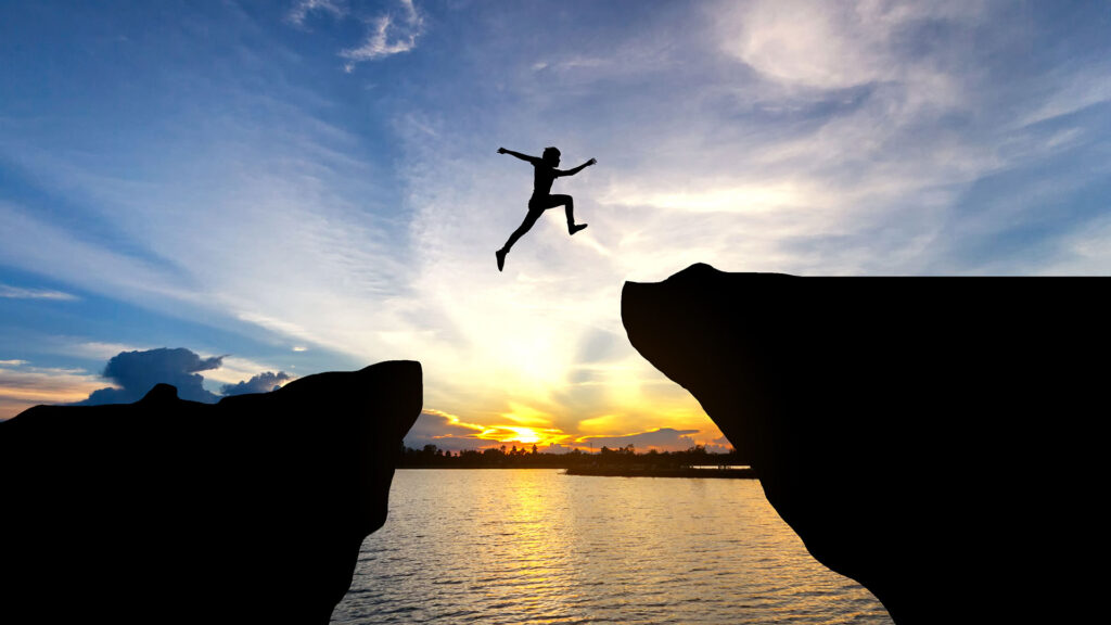 Person jumping over big gap between rocks